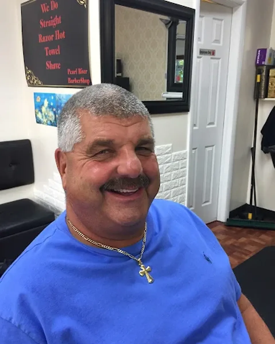 A smiling regular with a fresh cut in the chair at Pearl River Barber Shop