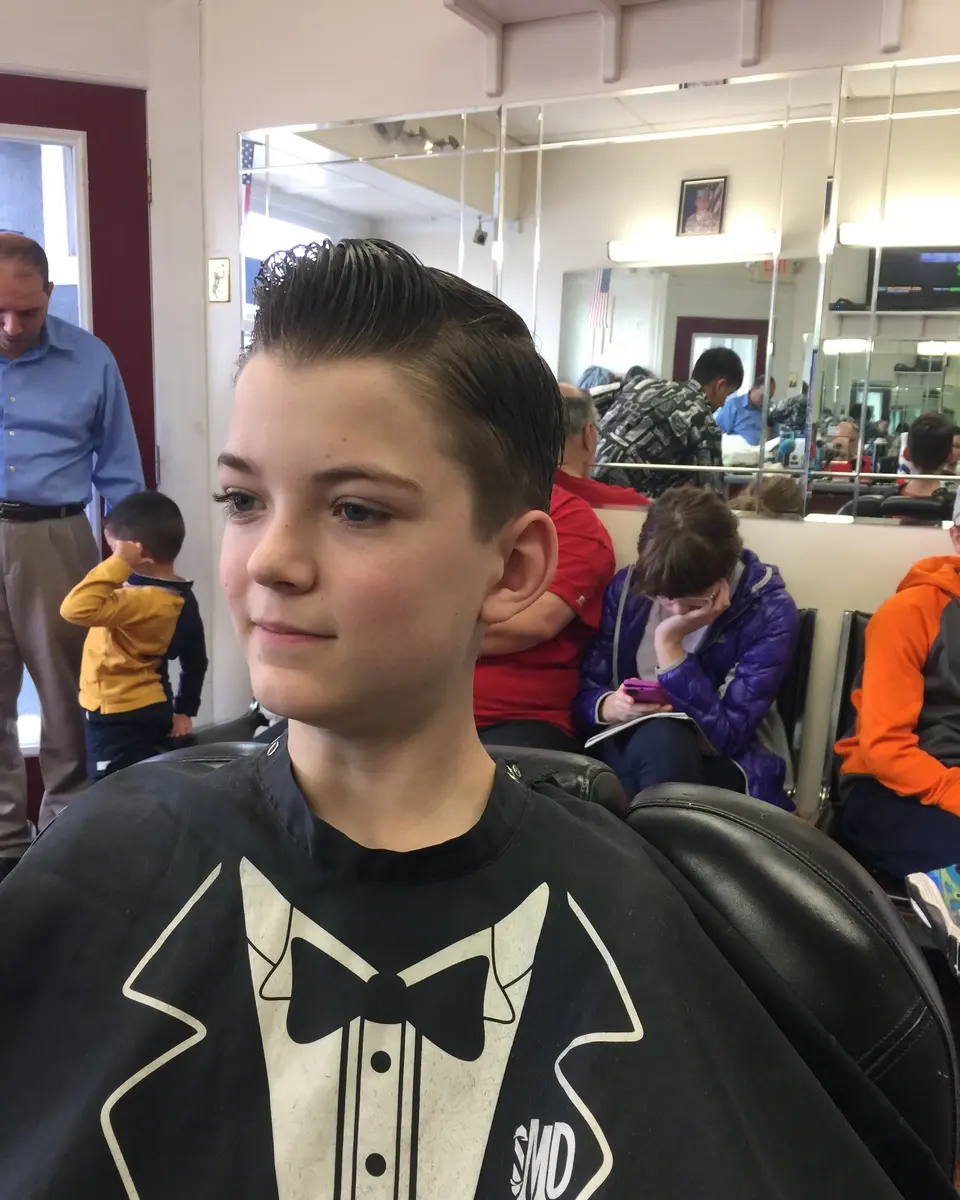 A boy with a fresh slicked-back cut in the chair at Pearl River Barber Shop
